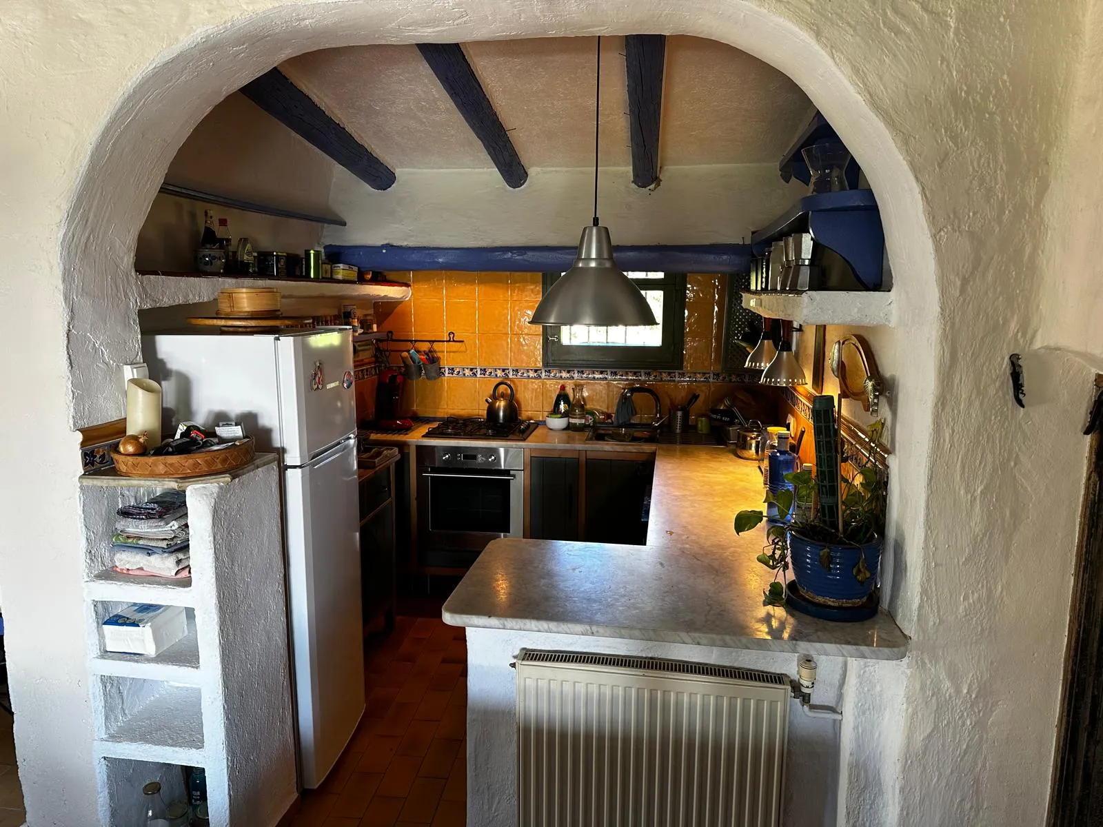 Cuisine rustique accessible par une arche en pierre